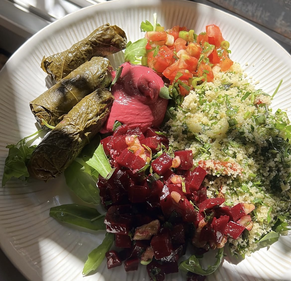 Assiette végétale : feuilles de vigne, houmous, taboulé, salade de betterave et noix, sauce tahini